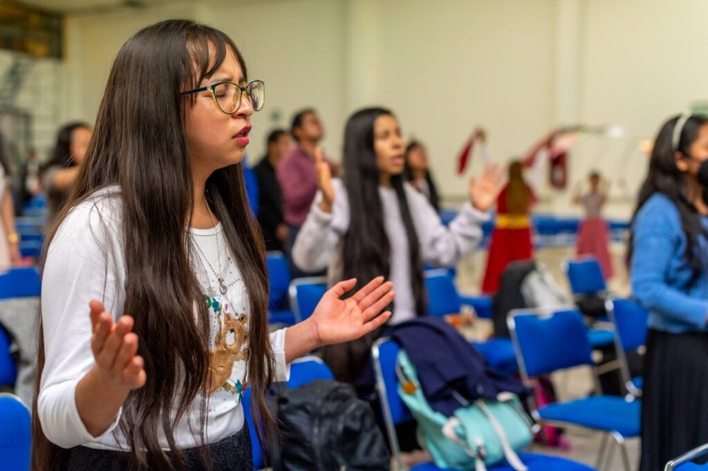 A girl in a classroom with her hands raised